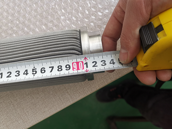 A worker is measuring the overall length of polymer melt filter element and it shows 931 mm.