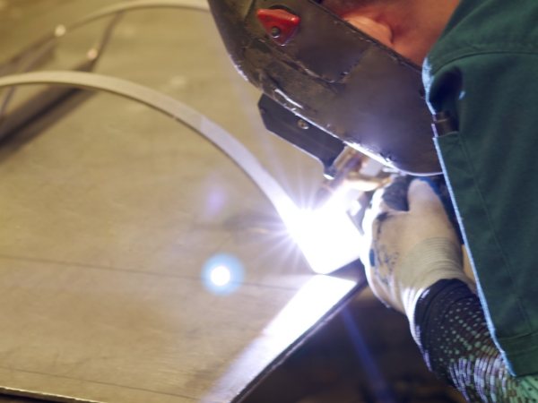 A worker is welding the metal part.
