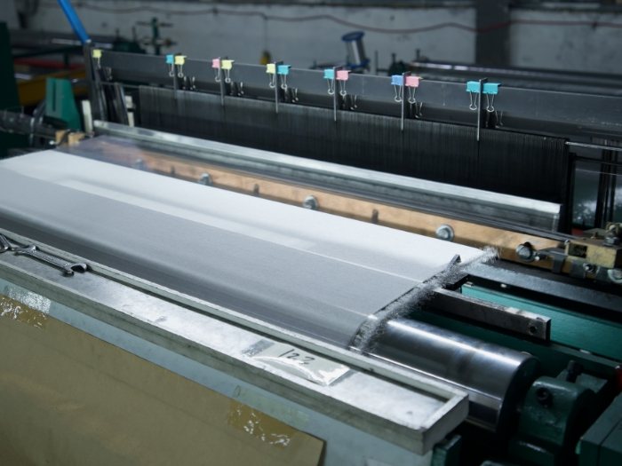 The machine is weaving metal wires into woven mesh.